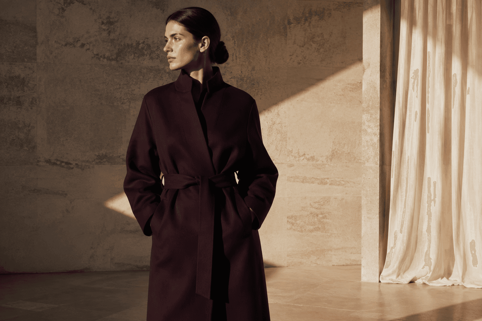 Mannequin en manteau aubergine dans une lumière architecturale chaleureuse
