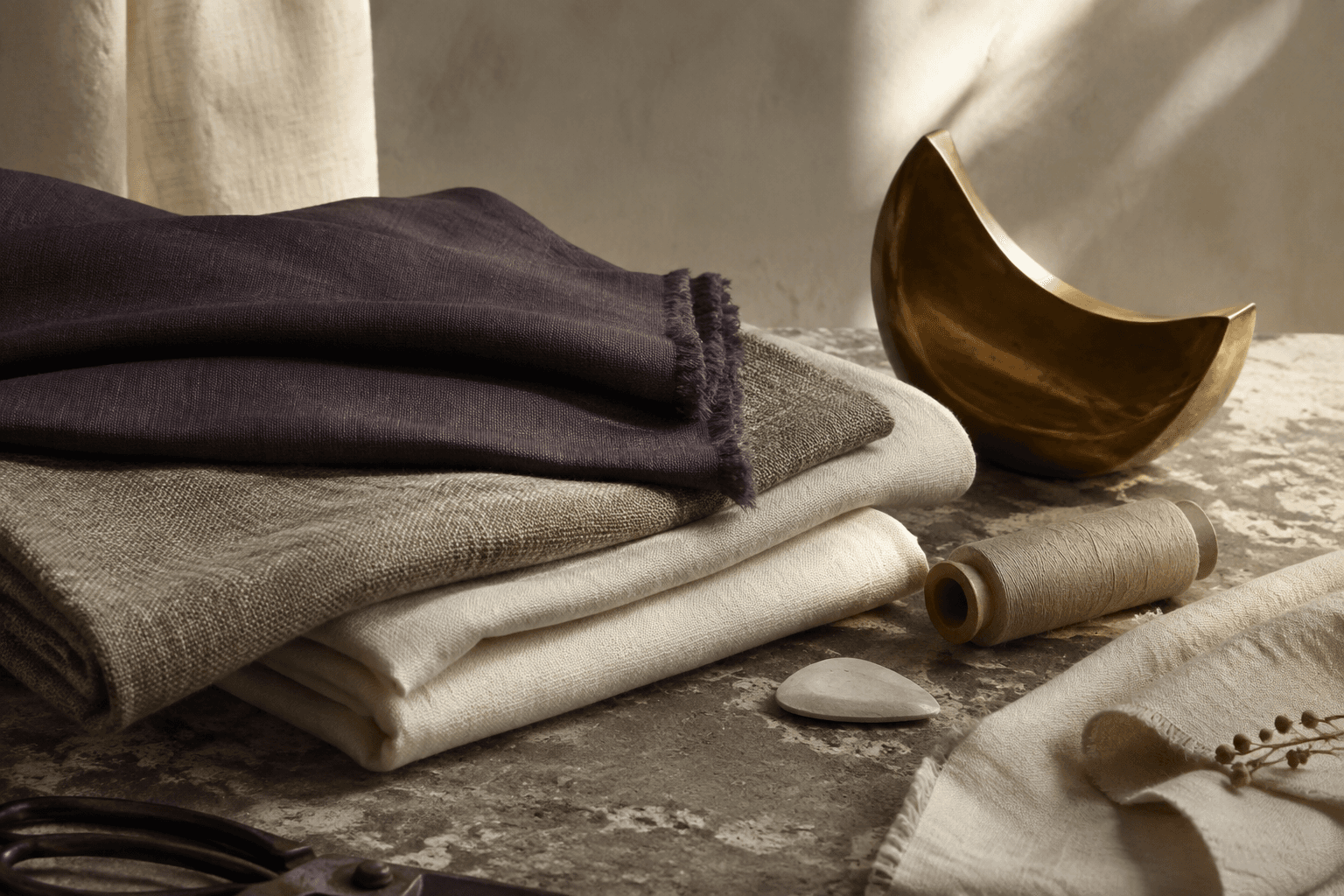 Textiles naturels, fil et objet en laiton sur pierre
